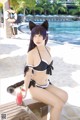 A woman in a black and white bikini sitting on a beach.